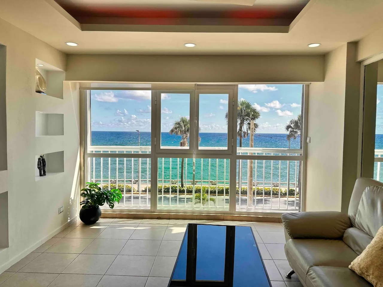 Living room with a leather sofa and windows on palms and the sea
