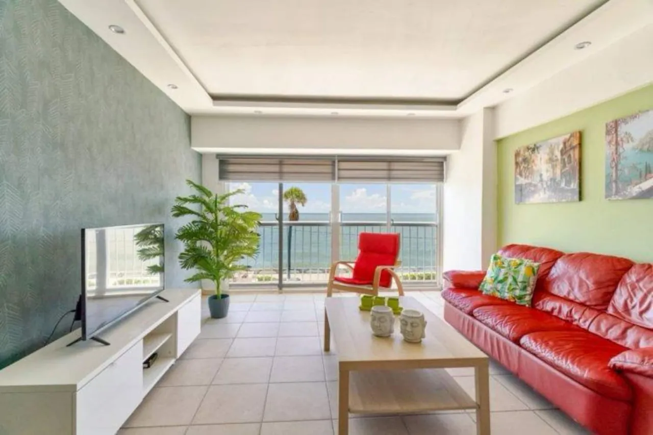 Bright living room with a red sofa and a sea view