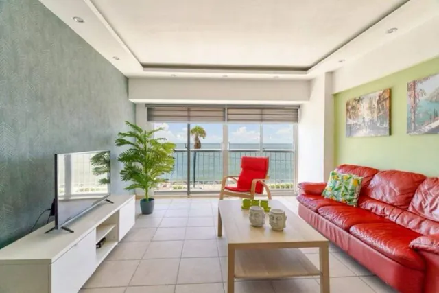Bright living room with a red sofa and a sea view