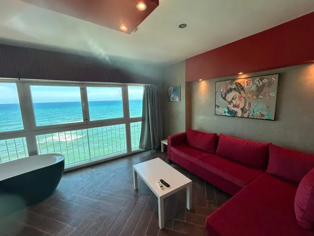 Living room with a red sectional and turquoise water through the windows