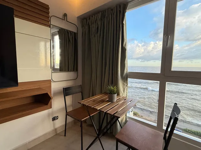 Small table and chairs at a window over the surf