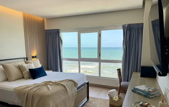 Bedroom with navy pillows and wide windows on the sea