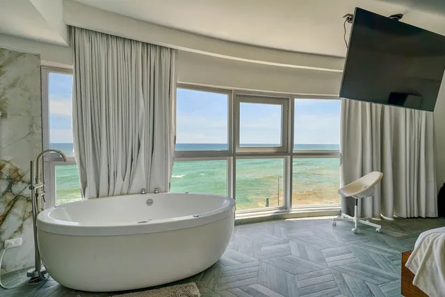Round jetted tub, marble walls and a sea view