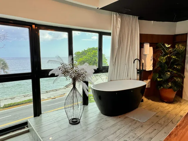 Black bathtub by windows looking down on the Malecón avenue and the sea
