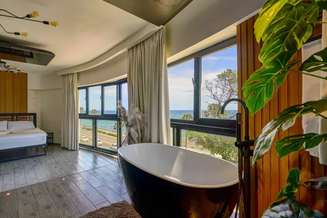 Loft with a black bathtub, plants and dark window frames over the Malecón