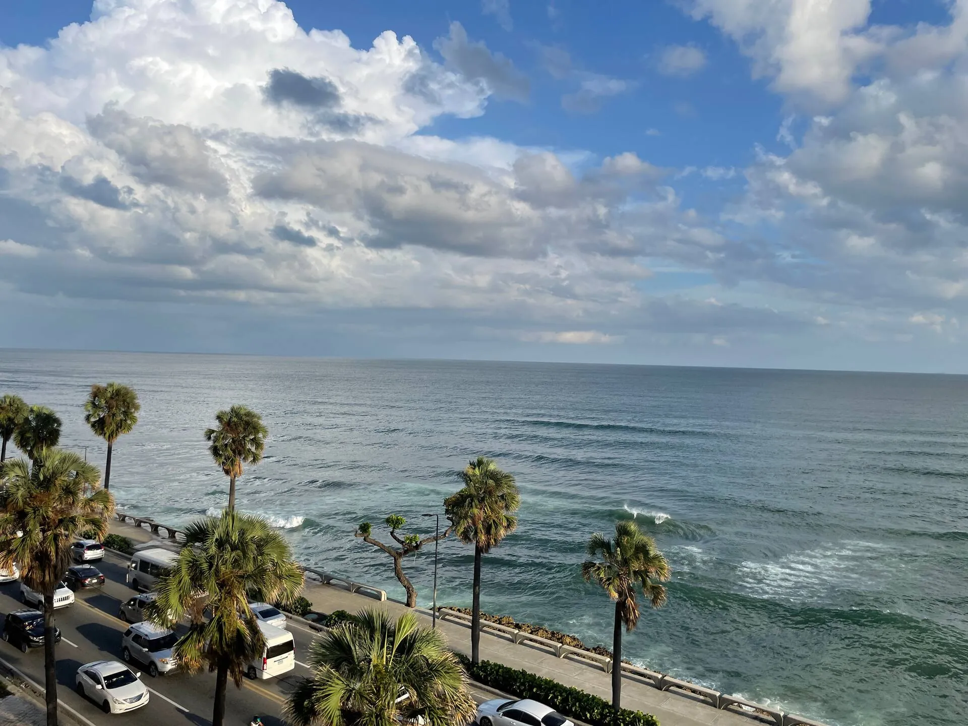 The Malecón seafront avenue and palm trees seen from an upper-floor Potenza apartment