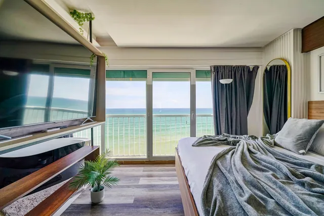 Penthouse bedroom with a wall of windows on the sea
