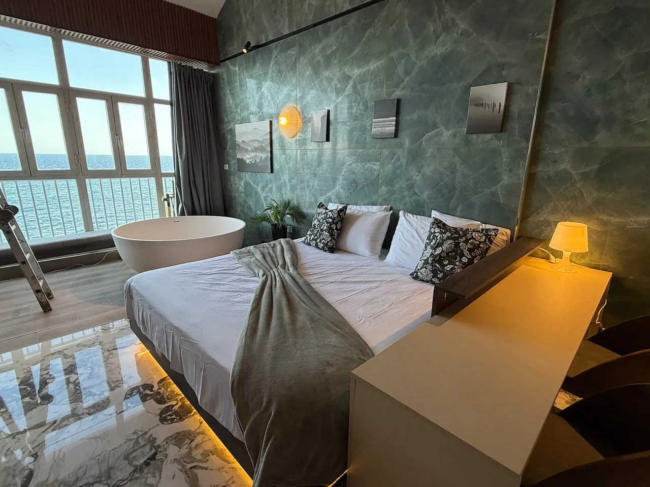 Penthouse with green marble walls, a tub and a bed facing the sea