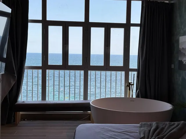 Penthouse bathtub under dark window frames and the sea
