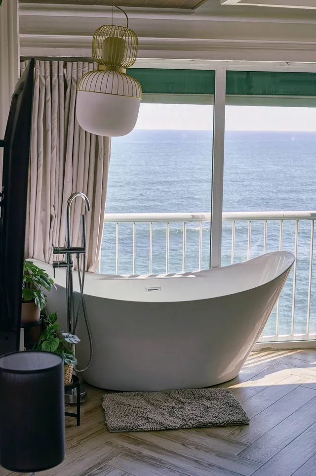 Slipper bathtub at the balcony door with the sea outside