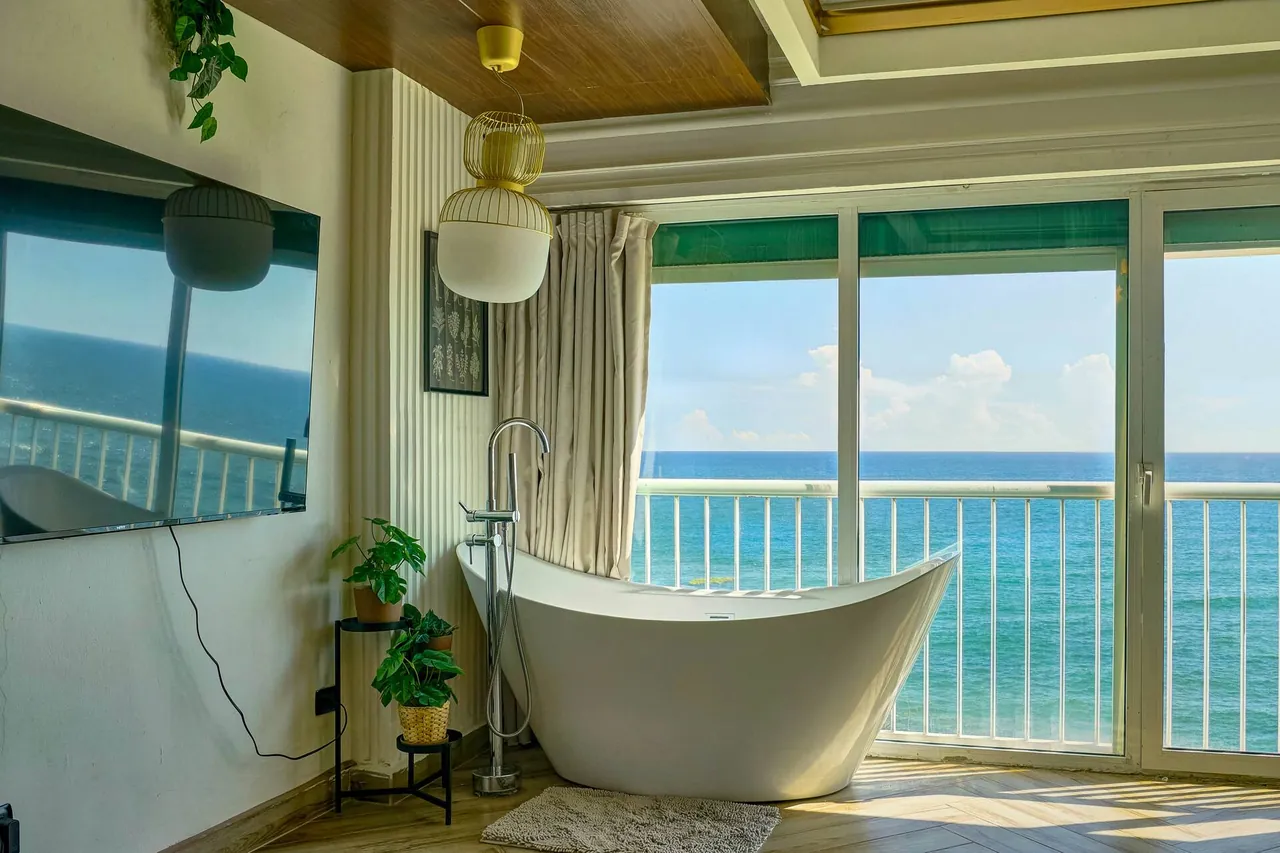 Slipper bathtub in front of balcony doors and turquoise water