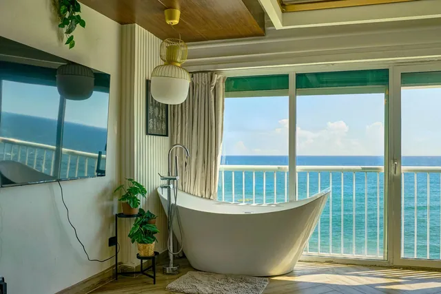 Slipper bathtub in front of balcony doors and turquoise water