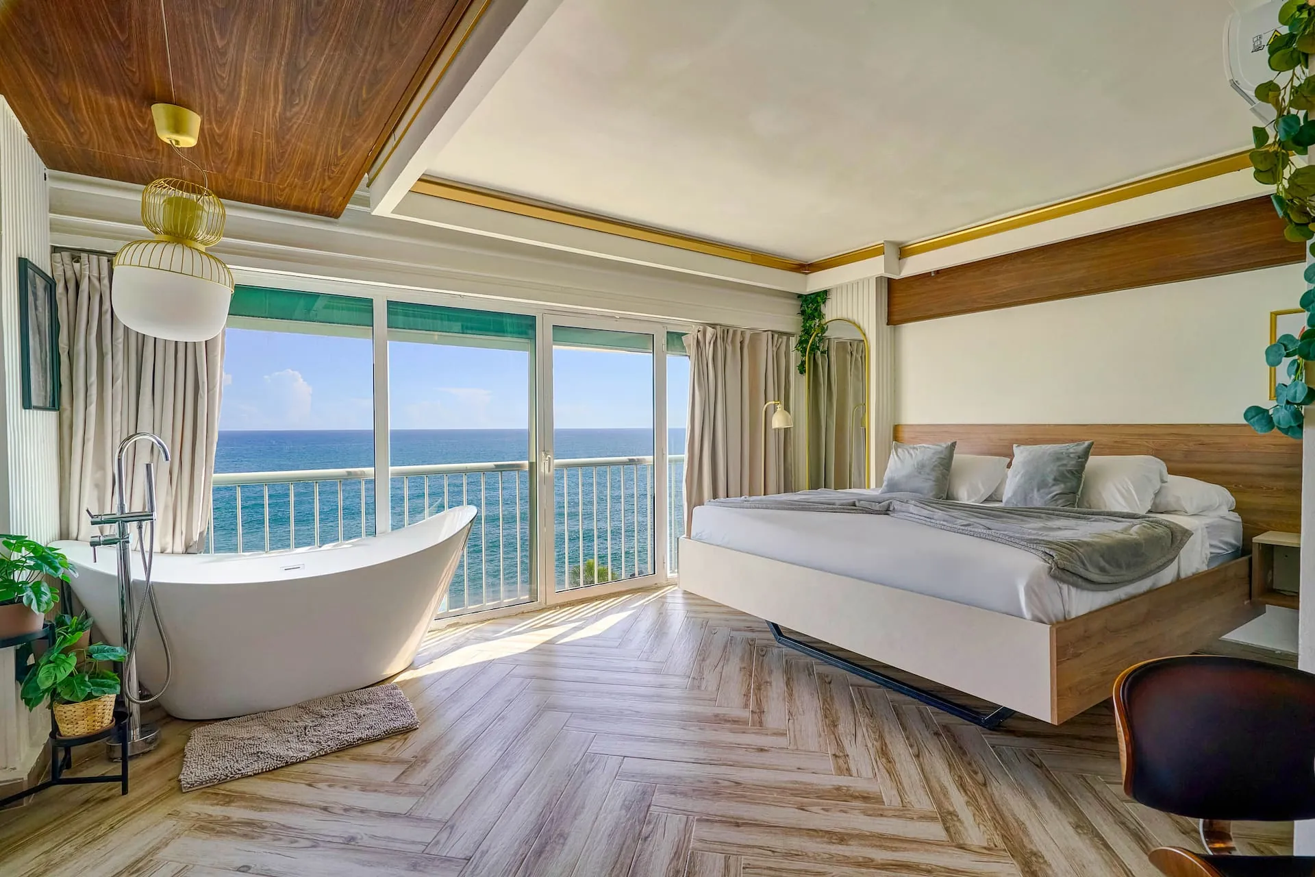 Studio with a slipper bathtub, king bed and wood-panel ceiling over the sea