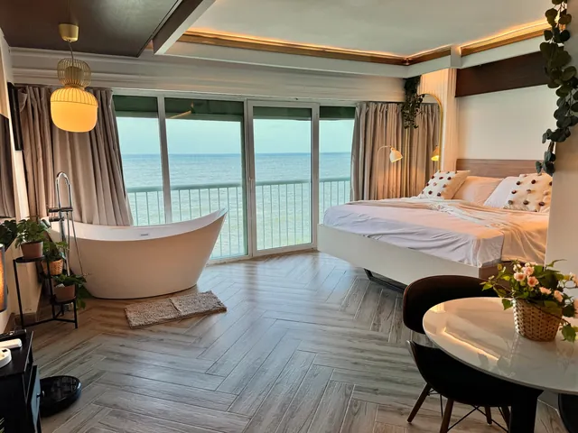 Bathtub, round table and bed in a bright sea-view studio