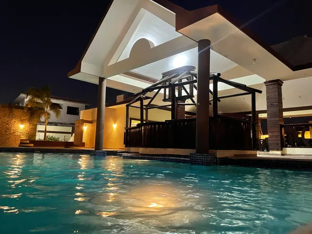 The villa pool lit at night beside the covered terrace