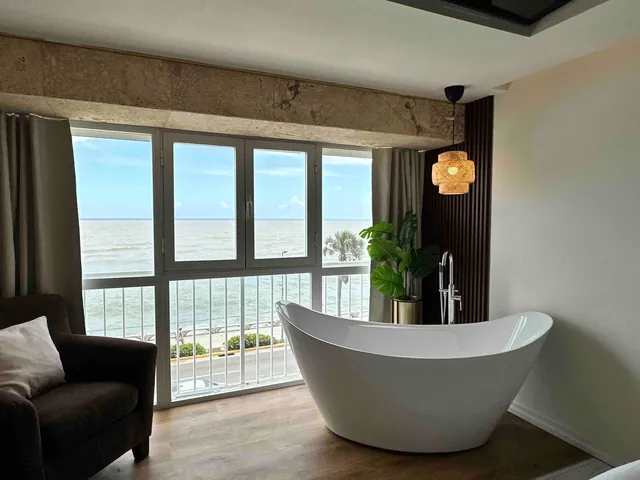 White slipper bathtub by the window with a rattan pendant lamp