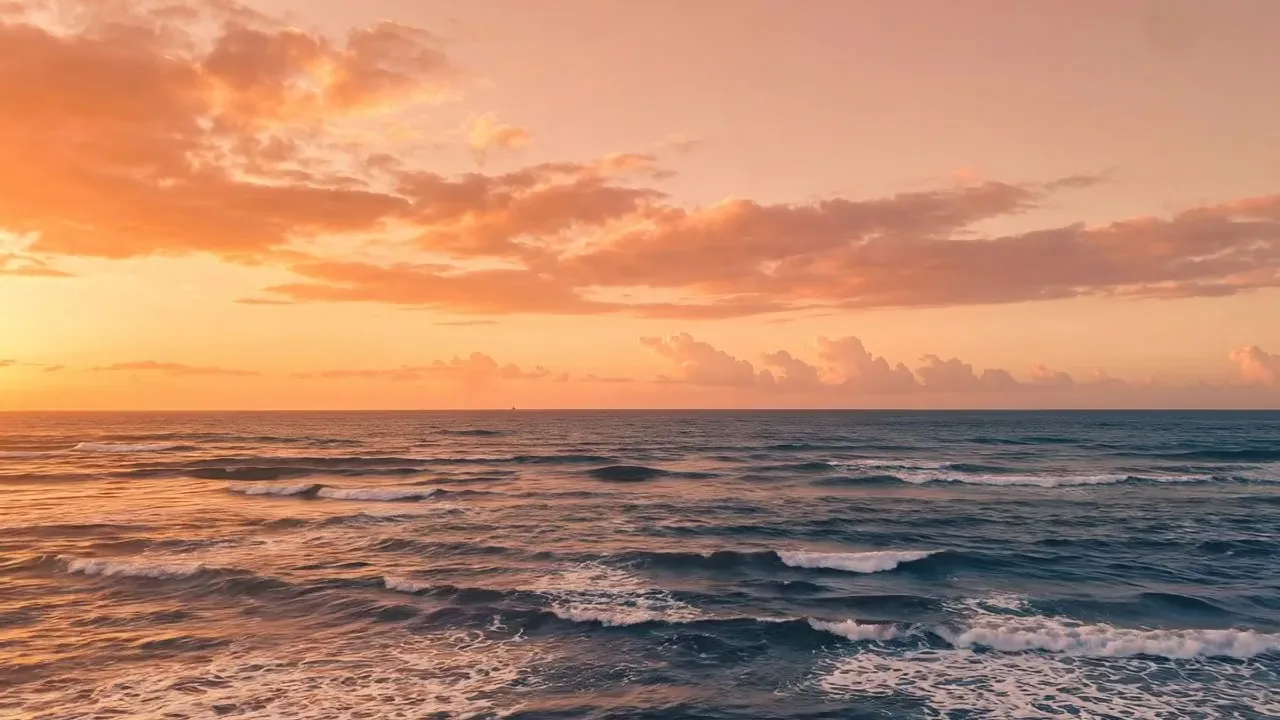 Waves rolling toward the Malecón of Santo Domingo under an orange sunset sky