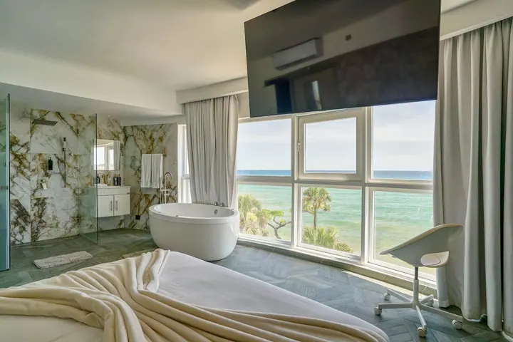 Loft with a round tub, marble bath wall and windows on the sea