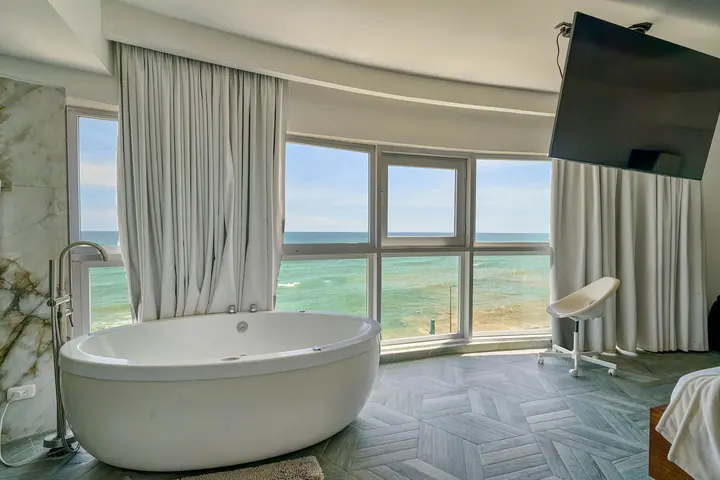 Round jetted tub, marble walls and a sea view