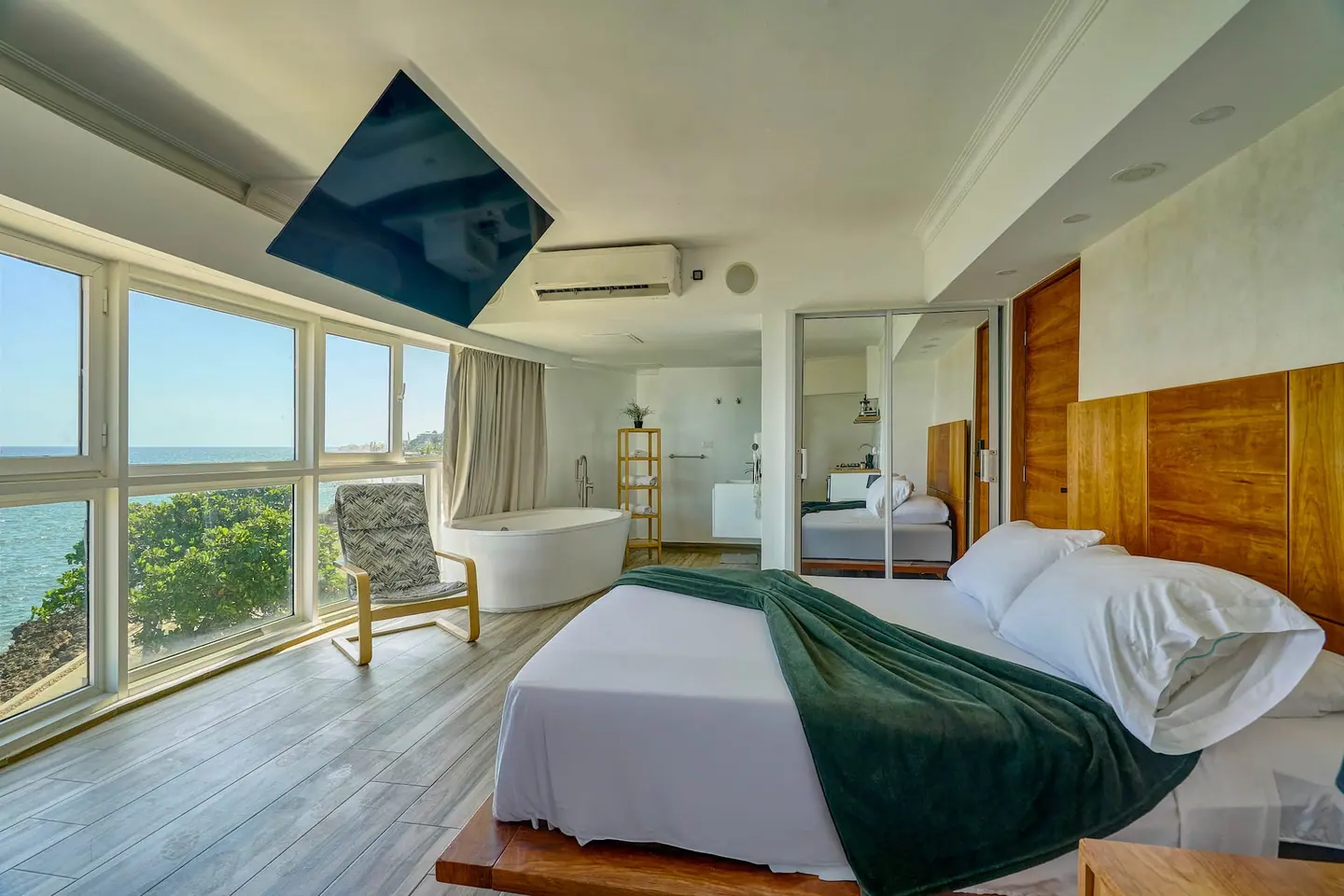 Loft bedroom with a green throw and a panorama of sea windows