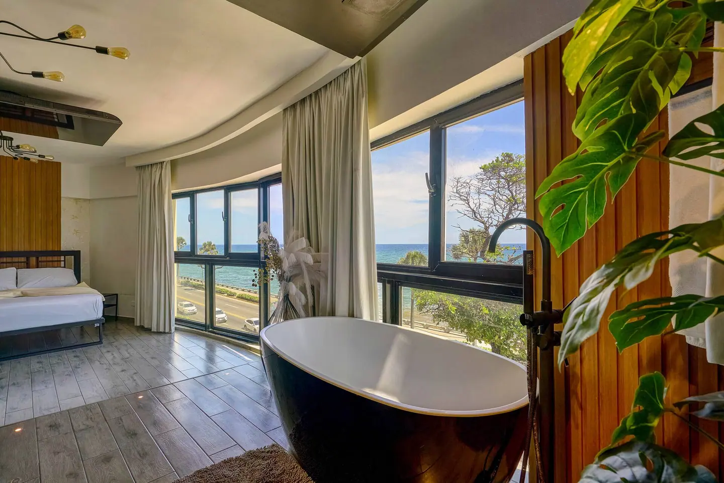 Loft with a black bathtub, plants and dark window frames over the Malecón