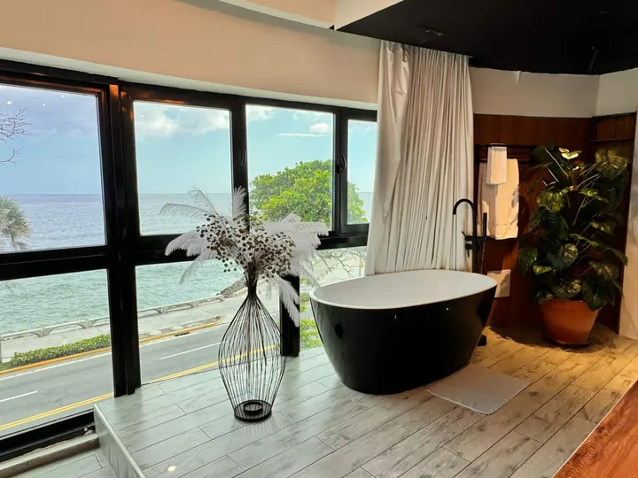 Black bathtub by windows looking down on the Malecón avenue and the sea