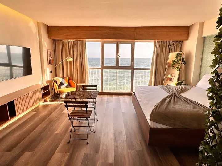Studio with wood floors, a dining set and windows on the sea