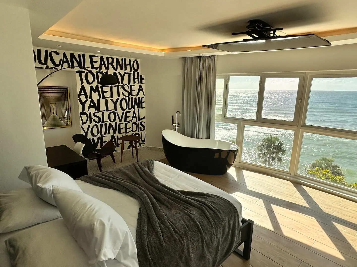 Loft with a painted word wall, black bathtub and sunlight from sea windows