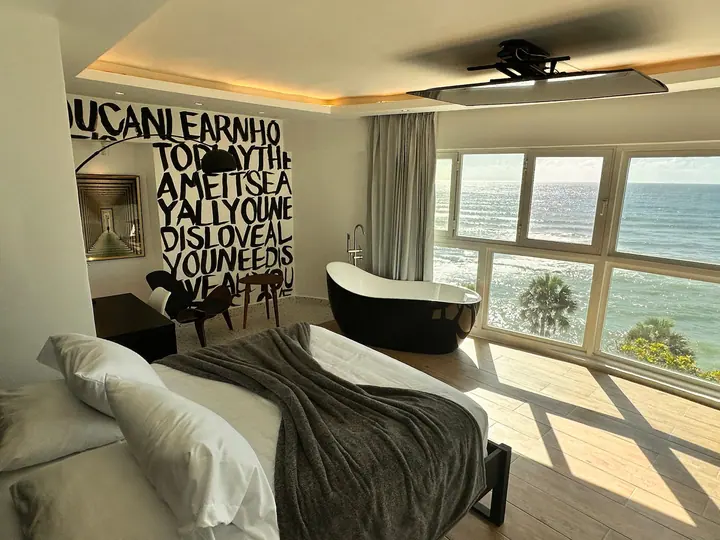 Loft with a painted word wall, black bathtub and sunlight from sea windows