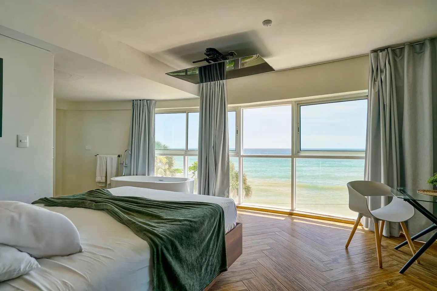 Loft bedroom with a green throw, bathtub and sea windows