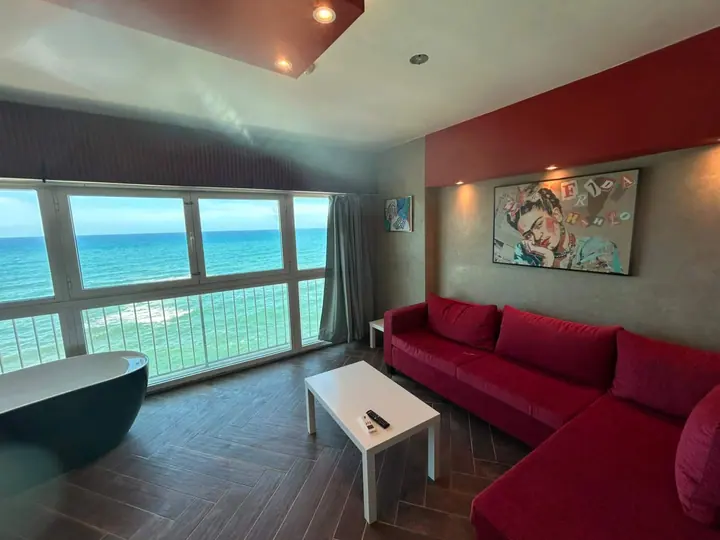 Living room with a red sectional and turquoise water through the windows
