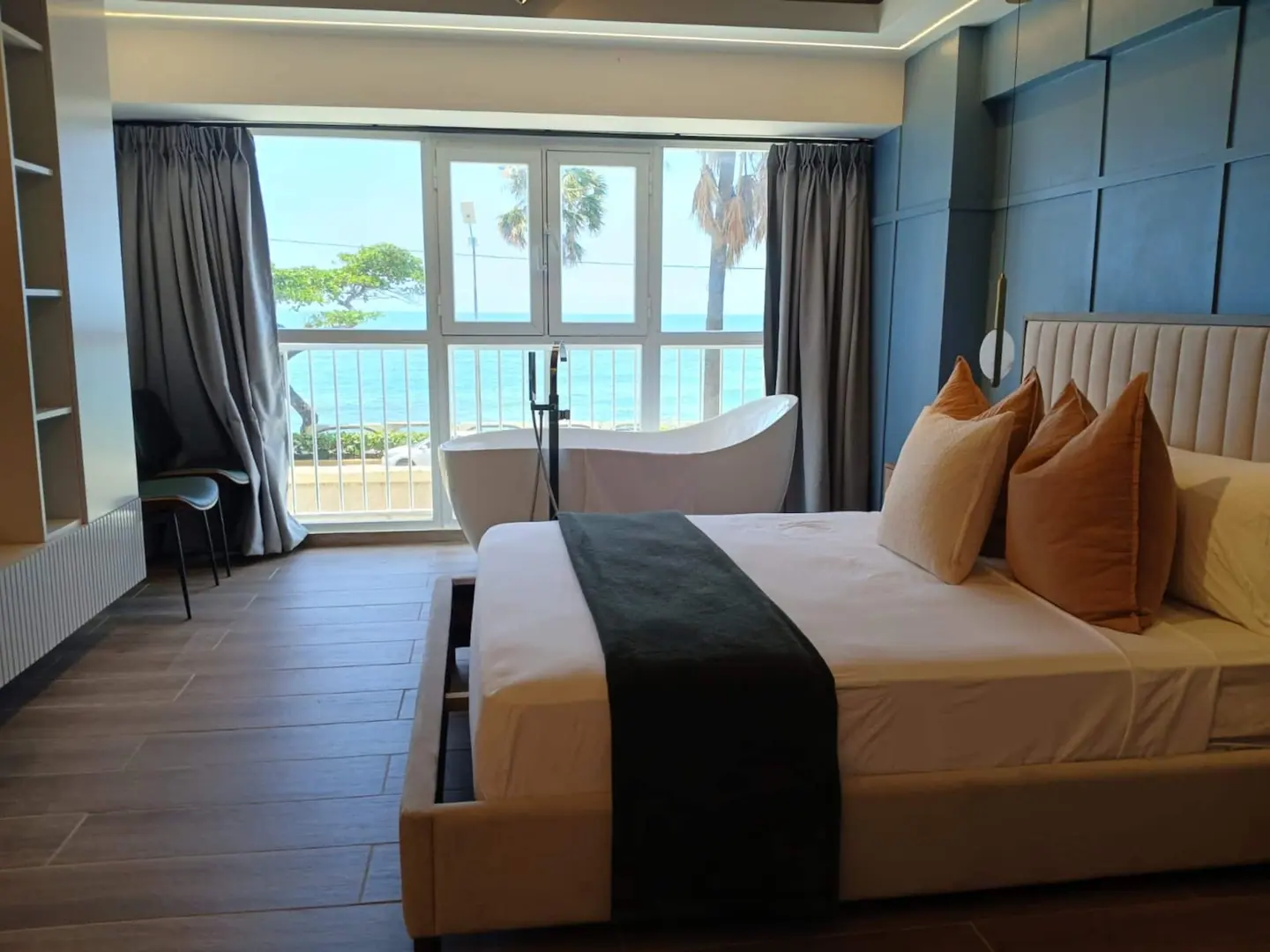 Bedroom with a freestanding tub and palms outside the window