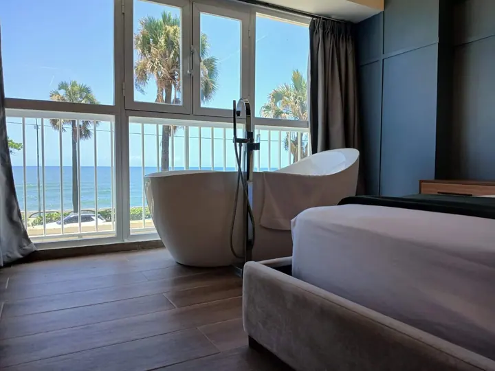 Bathtub and bed facing palms and the seafront