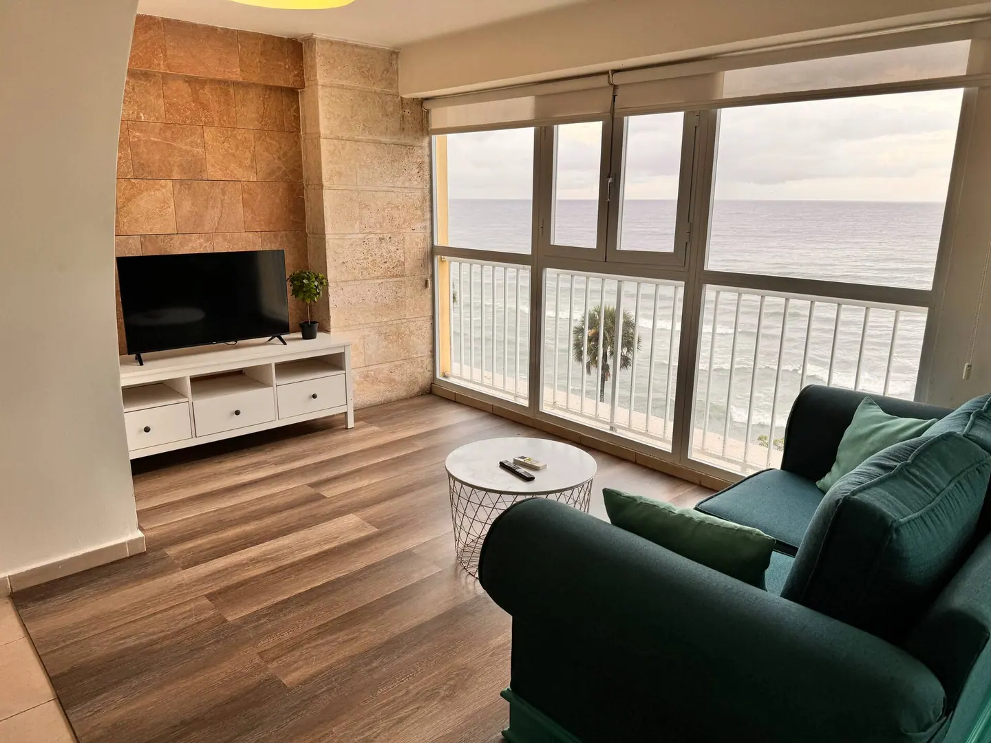 Living room with a green sofa and a long window on the sea