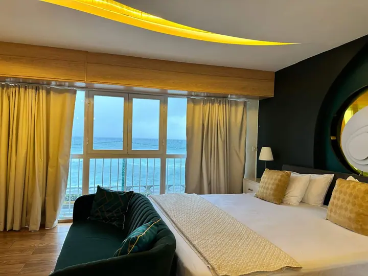 Bedroom with yellow curtains, a green sofa and the sea