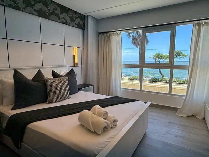 Bedroom with dark pillows and a window on the seafront