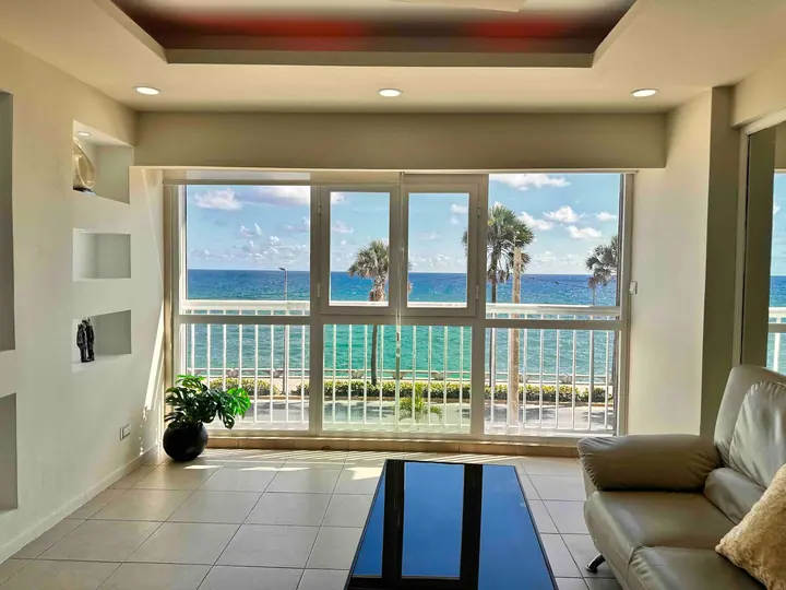 Living room with a leather sofa and windows on palms and the sea